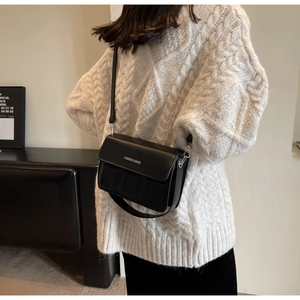 Detail of black rectangular crossbody bag featuring Fashion & Bags logo on a white sweater