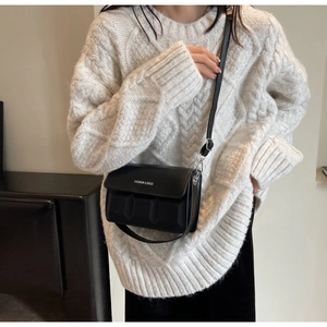 Close-up of black PU leather crossbody bag with geometric texture and white logo print