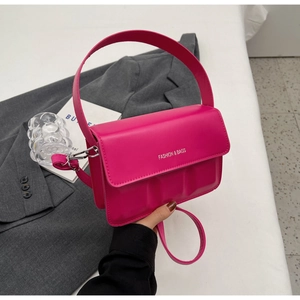 Detail of rose red leather crossbody bag featuring silver logo and detachable strap
