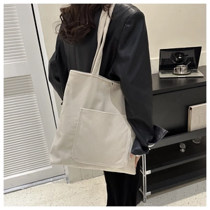 Detail of off-white corduroy tote bag showing soft texture and external pocket utility