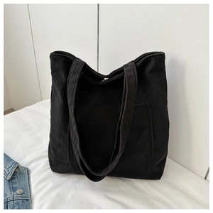 Macro detail of black corduroy tote bag showing textured fabric and front pocket