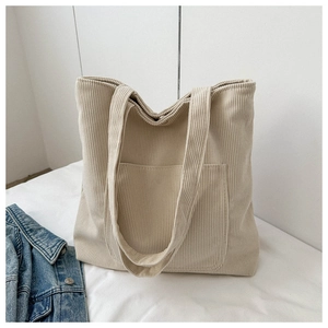 Detail of beige corduroy tote bag with vertical texture and large front utility pocket