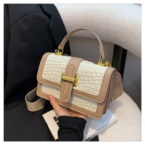 Close-up of woven texture handbag with golden H-clasp and elegant contrast beige trim