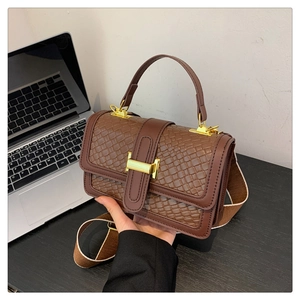 Detail of dark brown woven handbag featuring gold metal buckle and textured leather flap
