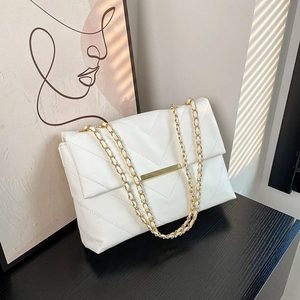 White quilted faux leather shoulder bag with gold chain strap on a minimalist black surface