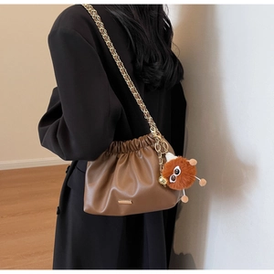 Brown soft leather bucket bag with gold chain strap and cute plush monster pendant