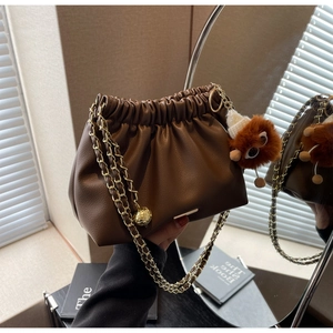 Brown pleated cloud bag with gold chain strap and cute plush monster charm accessory