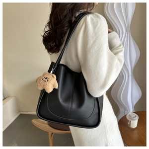 Close-up of black matte leather tote bag featuring a cute brown plush bear pendant