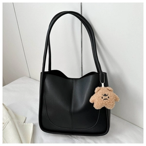 Close-up of black tote bag with U-shaped stitching and a cute plush bear pendant