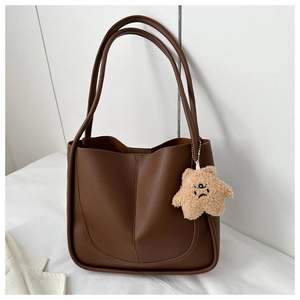 Detail of dark brown tote bag with U-shaped stitching and beige star plush charm