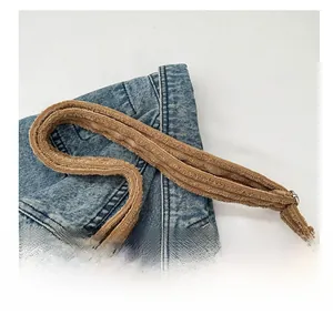 Détail de la bandoulière en peluche marron sur un sac fourre-tout en denim bleu et velours