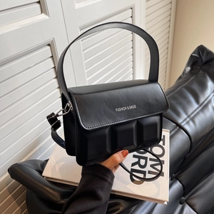 Black matte leather crossbody handbag with embossed cube detail and adjustable shoulder strap