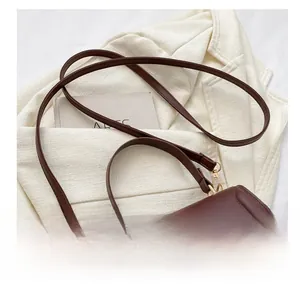 Macro view of a dark brown faux leather bag with adjustable strap and gold metal lock