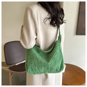 Détail de la texture du sac hobo en velours côtelé vert sur un mannequin en salle