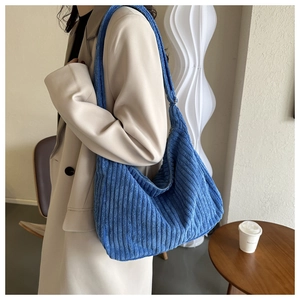 Texture détaillée du sac hobo en velours côtelé bleu porté avec un blazer décontracté beige