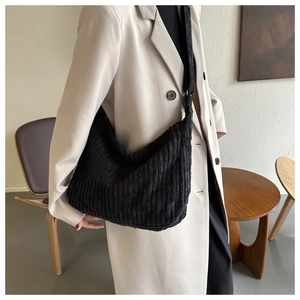 Gros plan du sac bandoulière en velours côtelé noir sur un blazer beige élégant