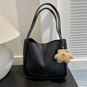 Vintage black large capacity tote bag with cute plush bear pendant on a neutral background