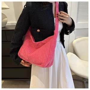 Détail d'un sac cabas en velours côtelé rose vif montrant sa texture douce et sa bandoulière