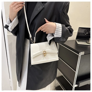 Chic white crossbody bag with gold ring buckle worn over a black leather jacket