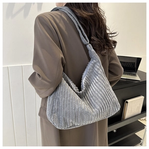 Détail du sac cabas en velours côtelé gris montrant la texture et la bandoulière sur modèle