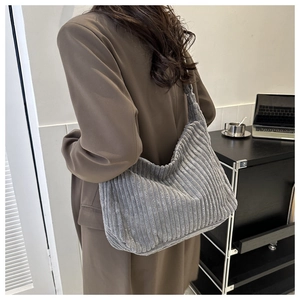 Détail de la texture en velours côtelé et sac hobo gris porté par un mannequin