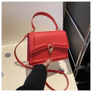 Close-up of red square handbag featuring golden oval buckle and detachable shoulder strap