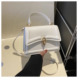 Close-up of white crossbody small square bag with elegant gold ring buckle detail