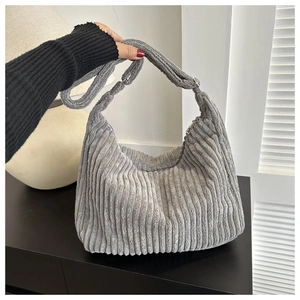Détail macro de la texture du velours côtelé gris et du design de ce sac hobo porté épaule