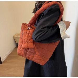 Detail of quilted brick red tote bag with matching coin purse and wide shoulder strap