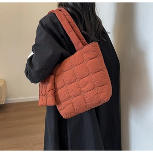 Detail of orange quilted tote bag with matching small pouch worn on the shoulder