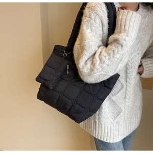 Détail du sac cabas matelassé noir avec pochette amovible sur un pull crème