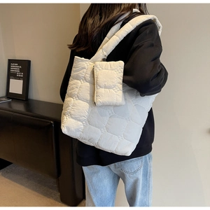 Gros plan du sac cabas matelassé crème avec pochette à chaîne sur l'épaule du mannequin