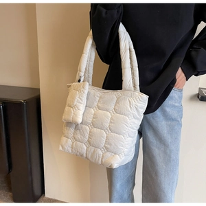 Detail of white quilted puffer tote bag with matching mini pouch and thick handles