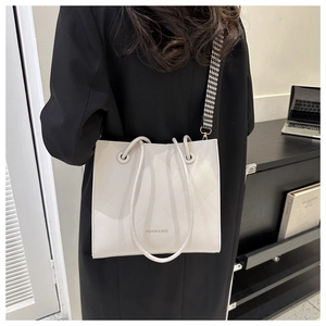 Dettaglio borsa tote trapuntata beige con tracolla pied de poule in un ufficio