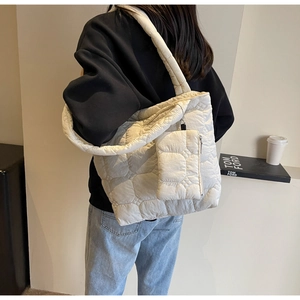 Detail view of large cream quilted tote bag with matching small pouch worn on shoulder