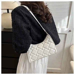 Detail of white faux leather shoulder bag with geometric woven texture worn by model