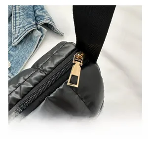 Detail shot of smooth gold zipper and black quilted puffer fabric on a trendy shoulder bag