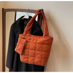 Detail of orange quilted tote bag with matching mini pouch and silver chain attachment