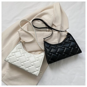 Detail showing woven texture of black and white shoulder bags on beige blazer
