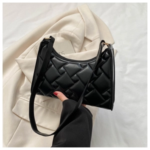 Detail of the black quilted shoulder bag with puffy woven texture on a beige blazer