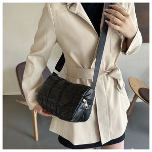 Detail of a black quilted puffer crossbody bag with adjustable wide shoulder strap