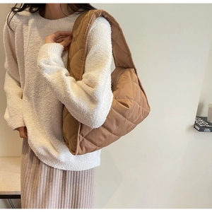 Détail du sac bandoulière matelassé marron avec coutures en losange et fermeture éclair