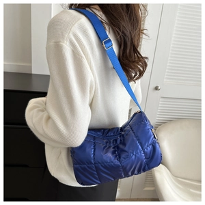 Close-up of royal blue quilted shoulder bag with glossy nylon and adjustable strap