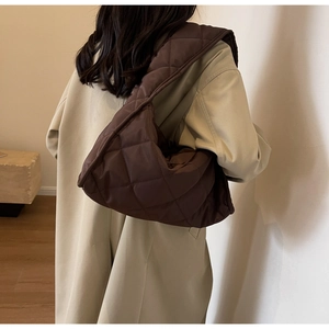 Détail du sac à bandoulière matelassé marron café porté par un mannequin en intérieur