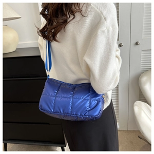 Blue quilted puffer crossbody bag with glossy finish and matching fabric shoulder strap