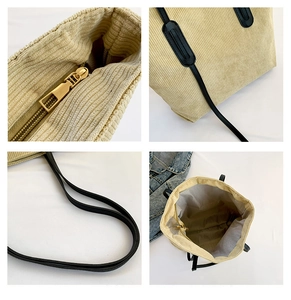 Detail view of beige corduroy tote bag showing gold zipper, black handles and lining