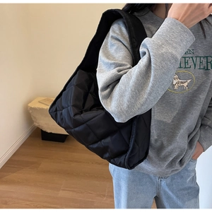 Détail d'un sac cabas noir matelassé avec texture en losanges et bandoulière large