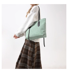 Detail of mint green corduroy tote bag featuring fine vertical texture and black handles