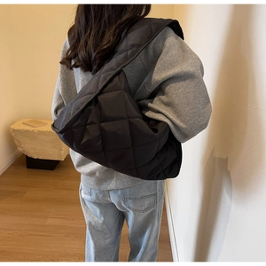 Vue arrière d'un sac bandoulière matelassé noir porté par un mannequin en studio