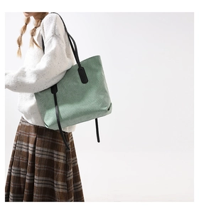 Close-up of mint green corduroy tote bag texture with black leather shoulder handles